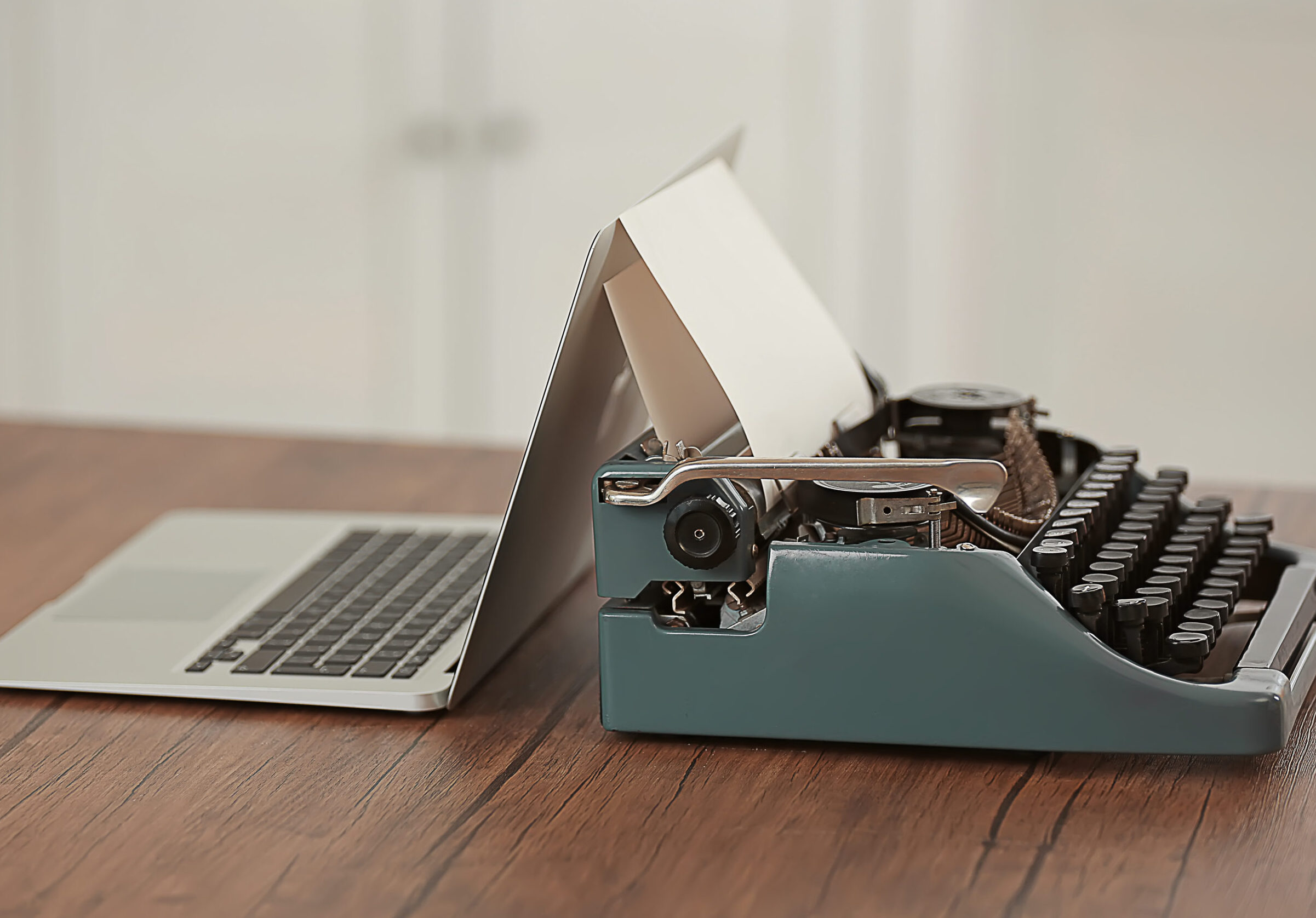 Laptop und Schreibmaschine auf einem Holztisch